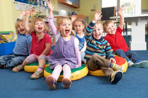 Groups of kindergarteners raising their hands